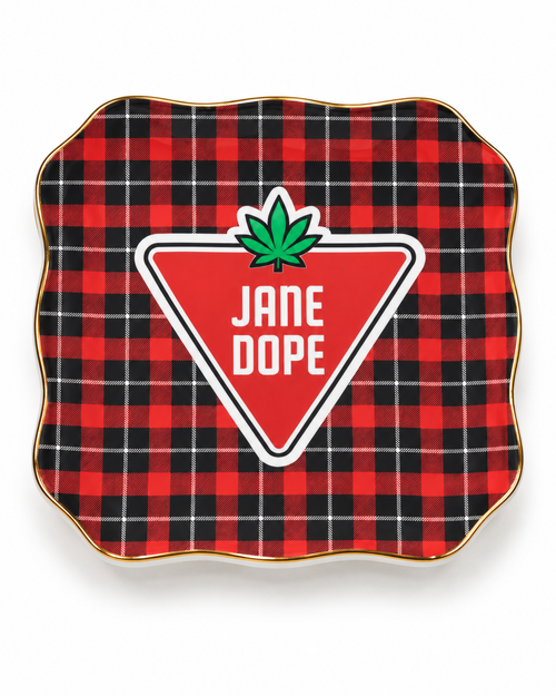 A square decorative plate with scalloped edges, featuring a red and black buffalo plaid pattern with a gold rim. In the center is a red triangular badge with white text reading 'JANE DOPE' and a green cannabis leaf above it.