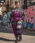 A woman stands on a city street wearing a matching oversized hoodie and jogger pants set in black, white, and bright pink graffiti-style text. The background shows a graffiti-covered brick wall.