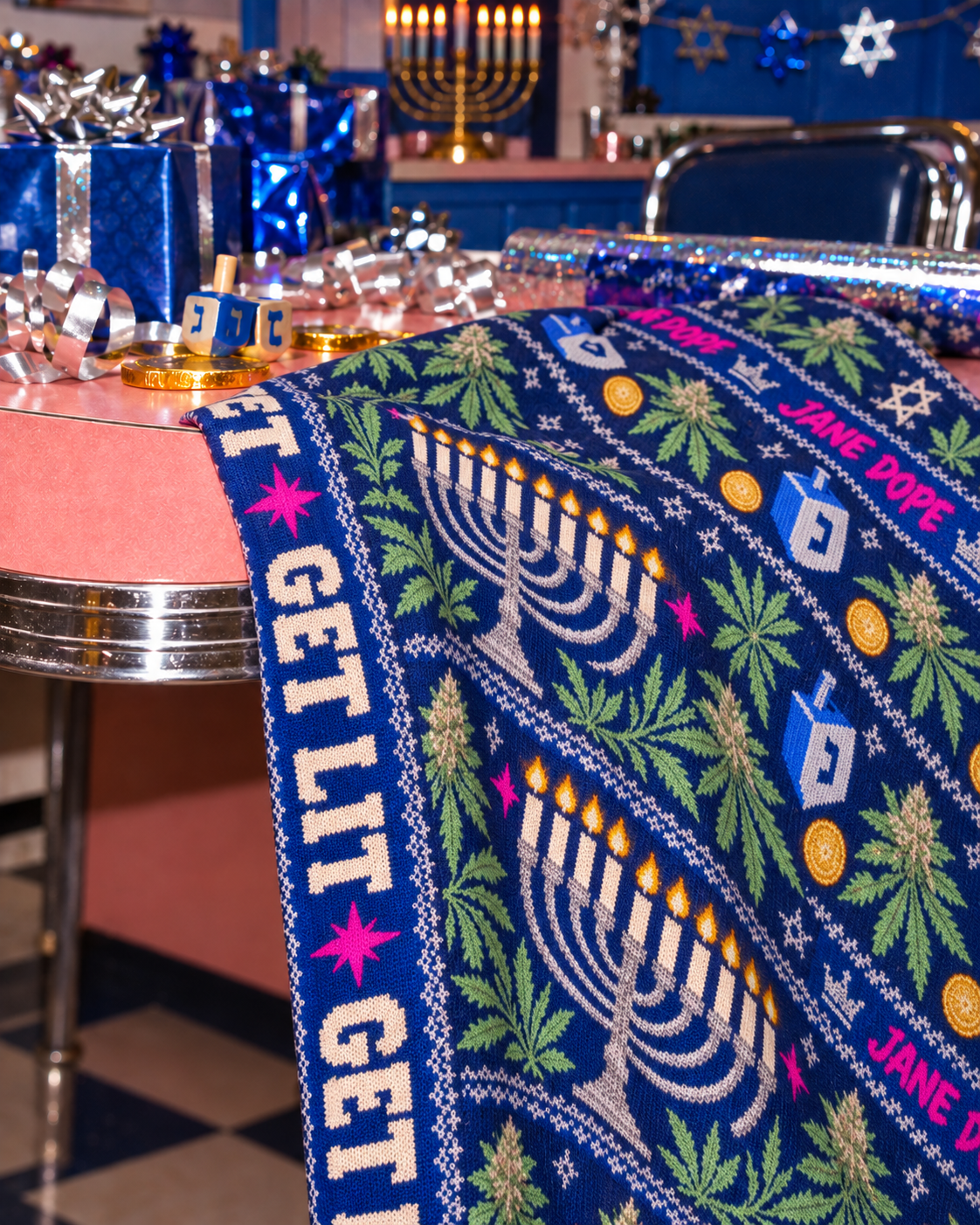Close-up of softly folded Get Lit scarf fabric, showing the blue botanical print, menorah motif and cream lettering.