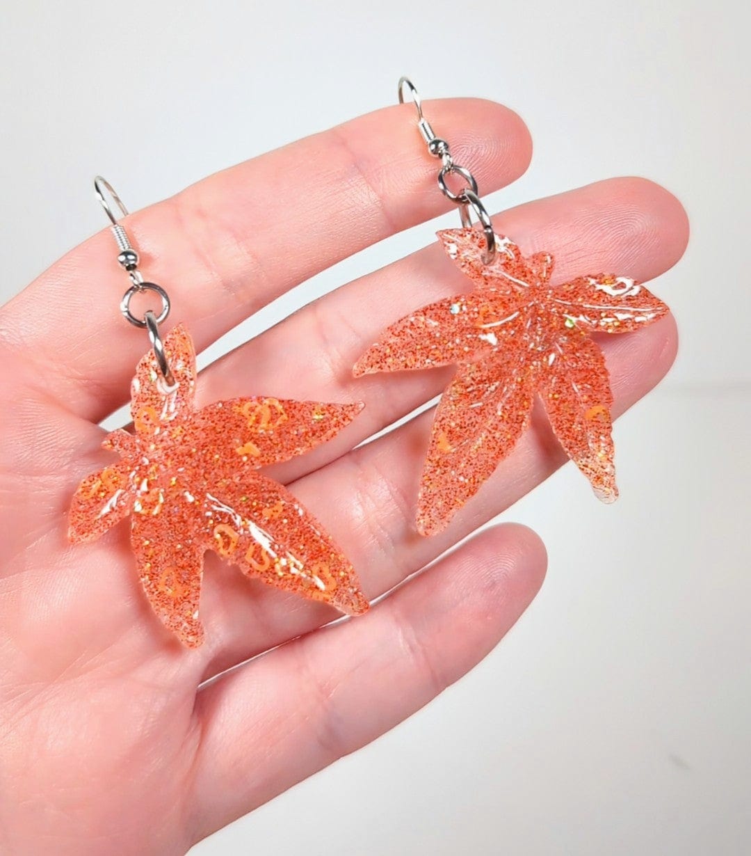 Glitter moonstone cannabis leaf earrings in orange, close-up
