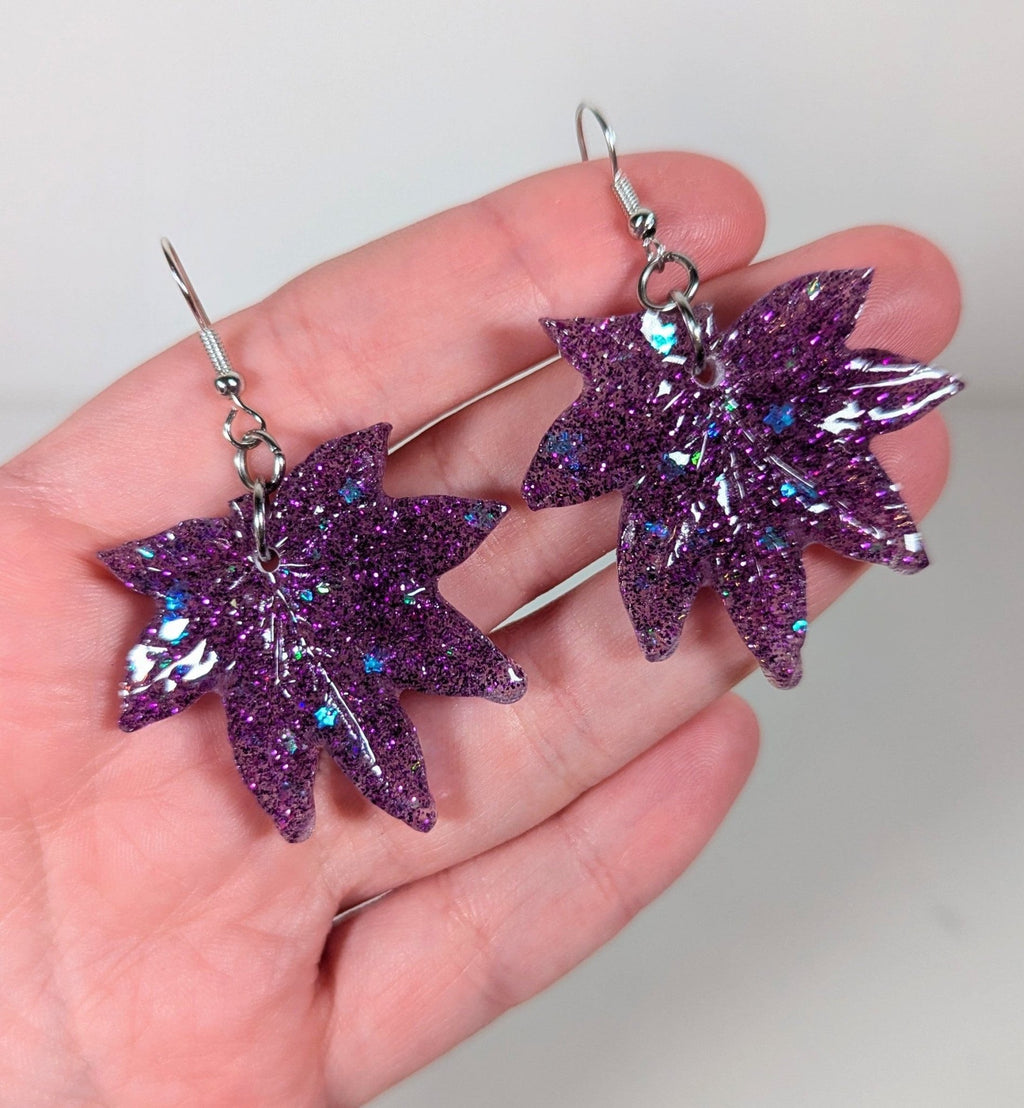 Glitter moonstone cannabis leaf earrings in purple, close-up
