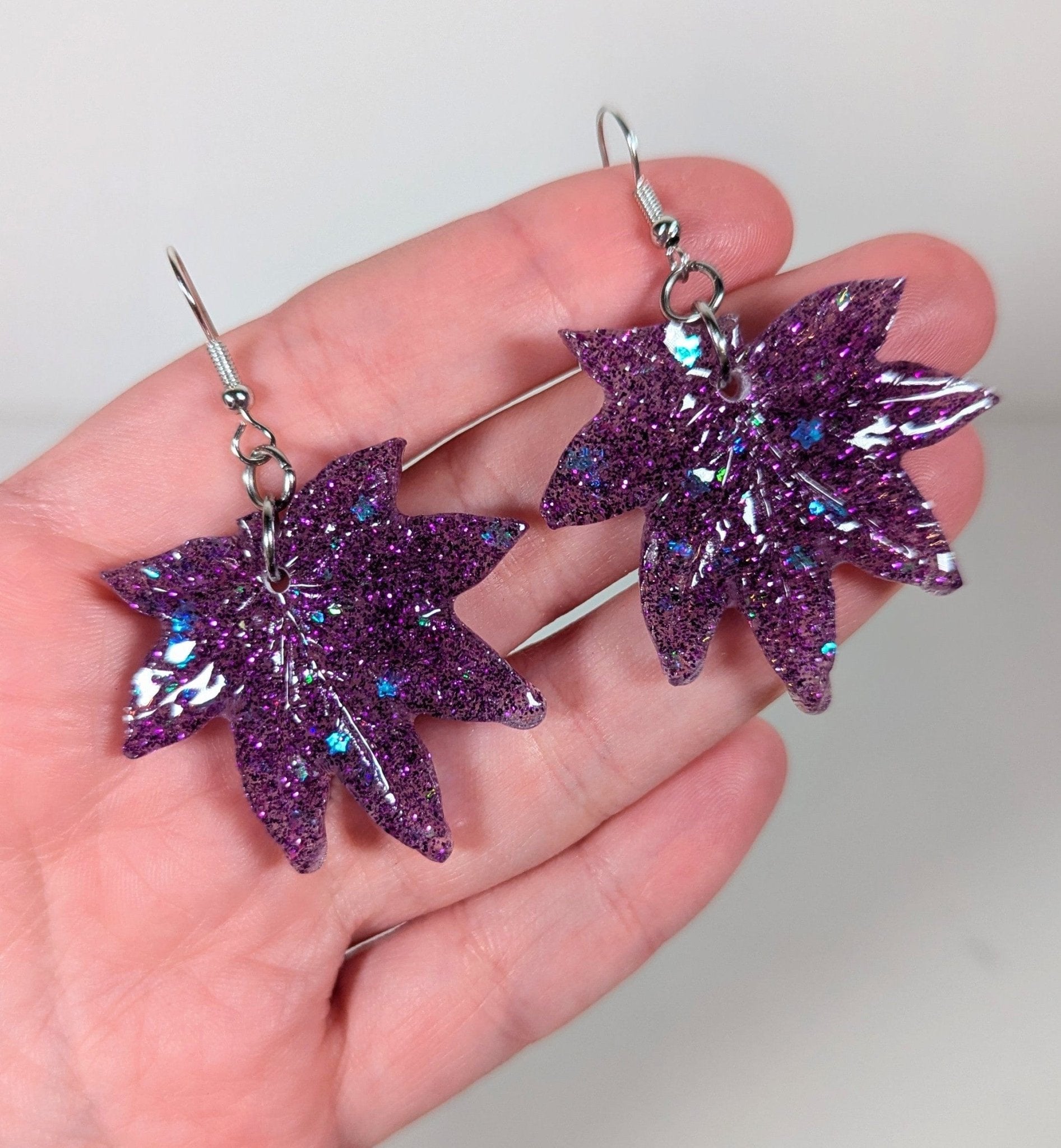 Glitter moonstone cannabis leaf earrings in purple, close-up