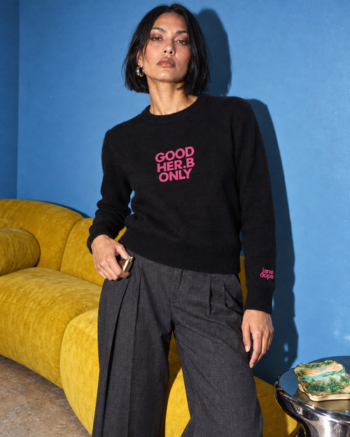 Jane Dope GOOD HER.B ONLY unisex knit sweater in Black. House rules detail: flash editorial on a blue-wall, yellow-sofa set.