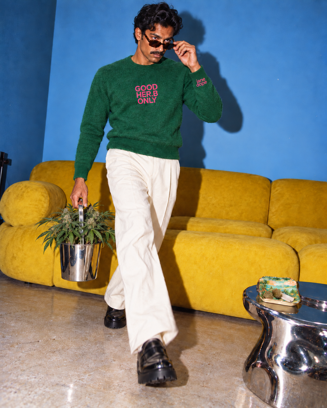 Jane Dope GOOD HER.B ONLY unisex knit sweater in Forest. Plant parent: flash editorial on a blue-wall, yellow-sofa set.