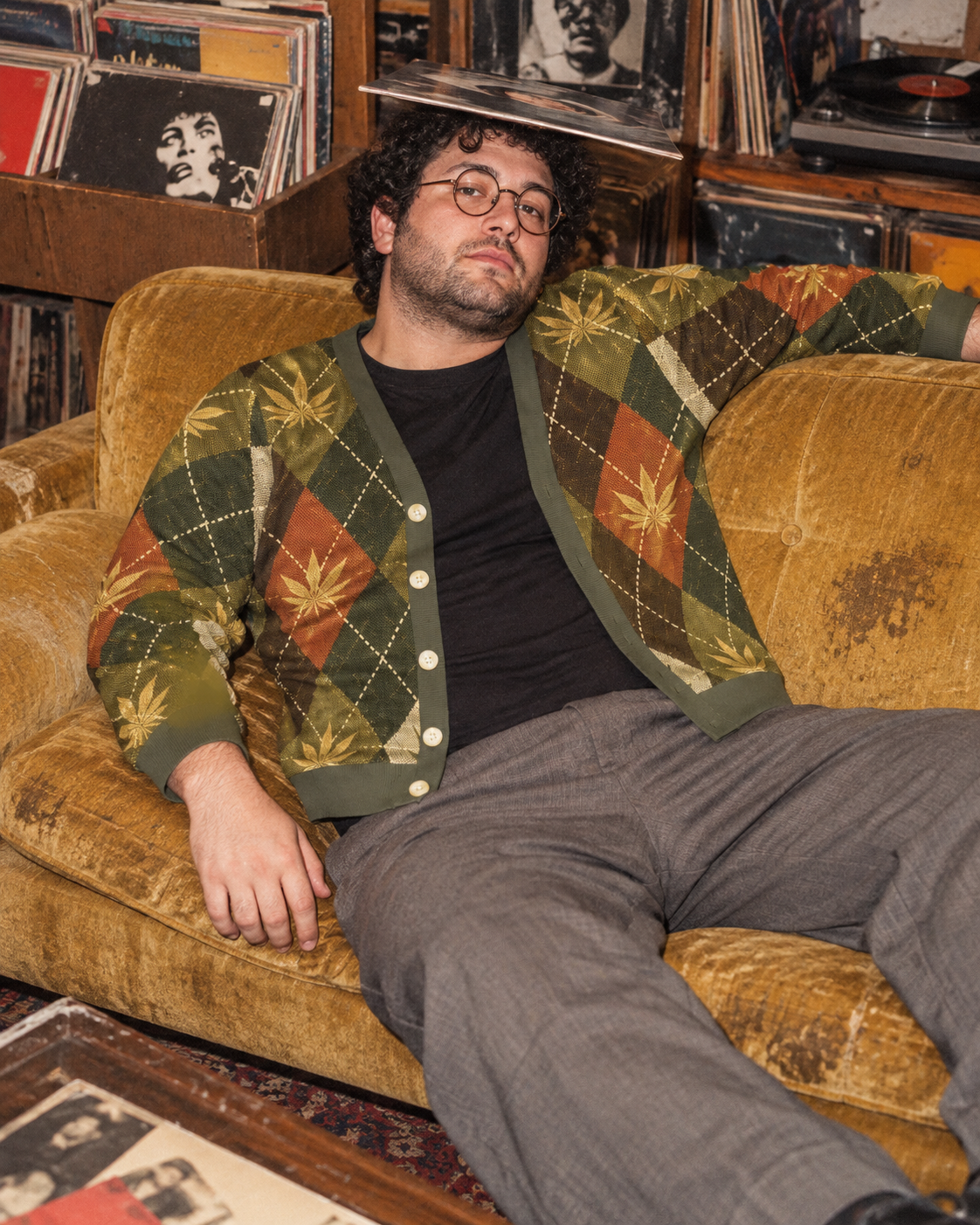 Open argyle cardigan on a model lounging on a mustard sofa