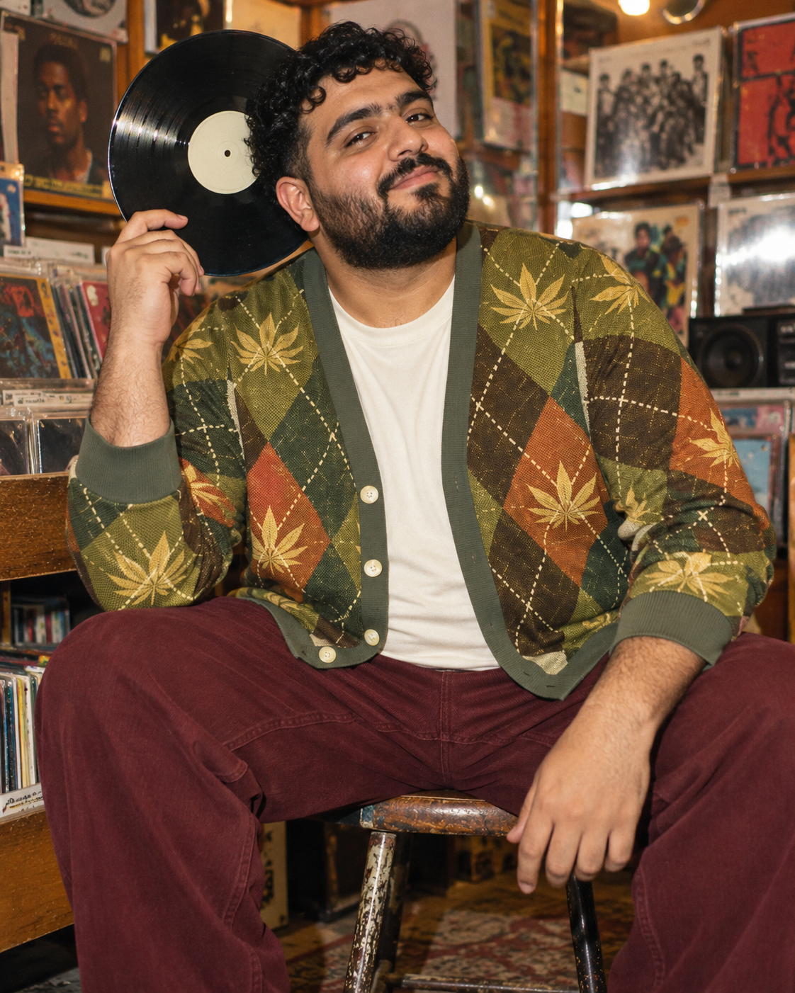 Argyle cardigan with cream tee and burgundy trousers on a seated model