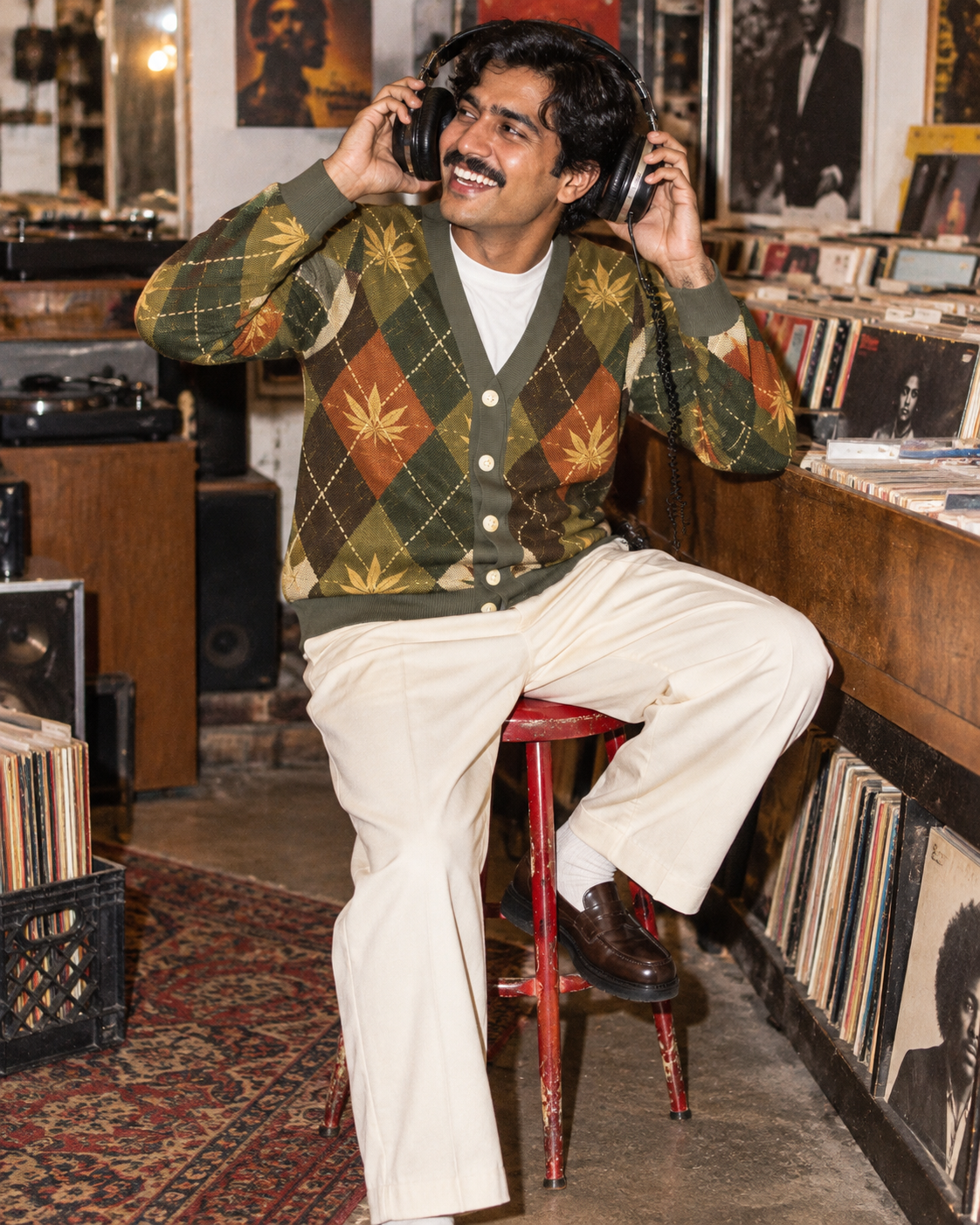 Buttoned argyle cardigan with cream trousers and headphones