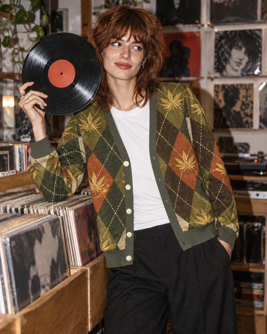 Argyle cardigan worn open with a white tee while browsing vinyl