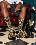 Batik Buds men's socks with green botanical paisley print styled with charcoal shorts on an oxblood sofa