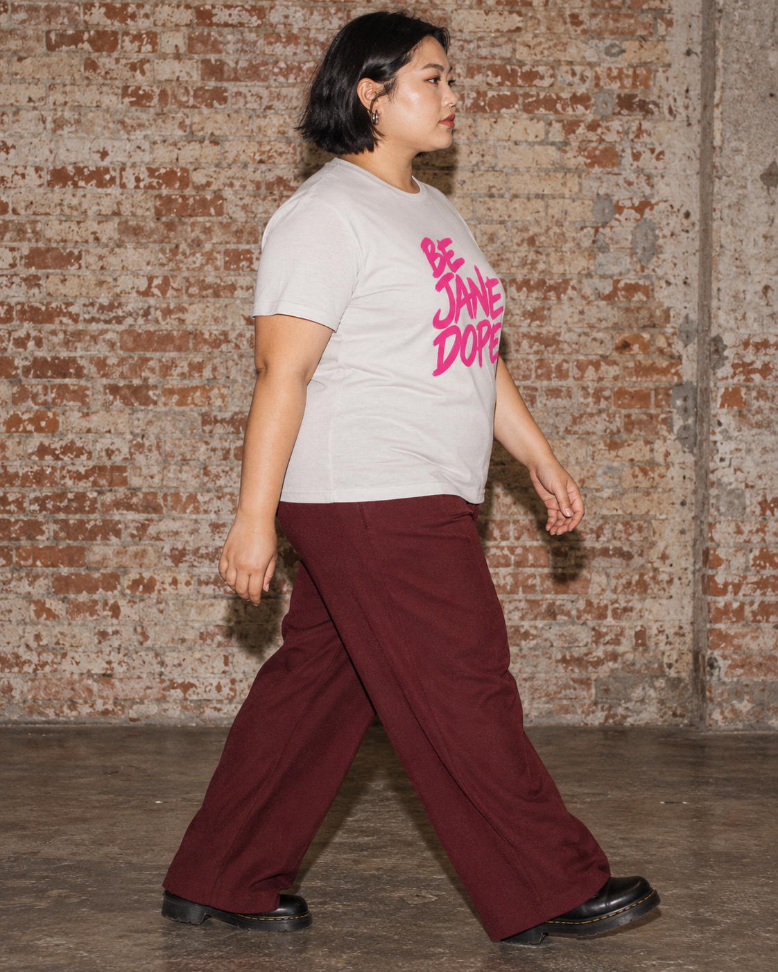 Side view of BE JANE DOPE tee with burgundy wide-leg trousers.