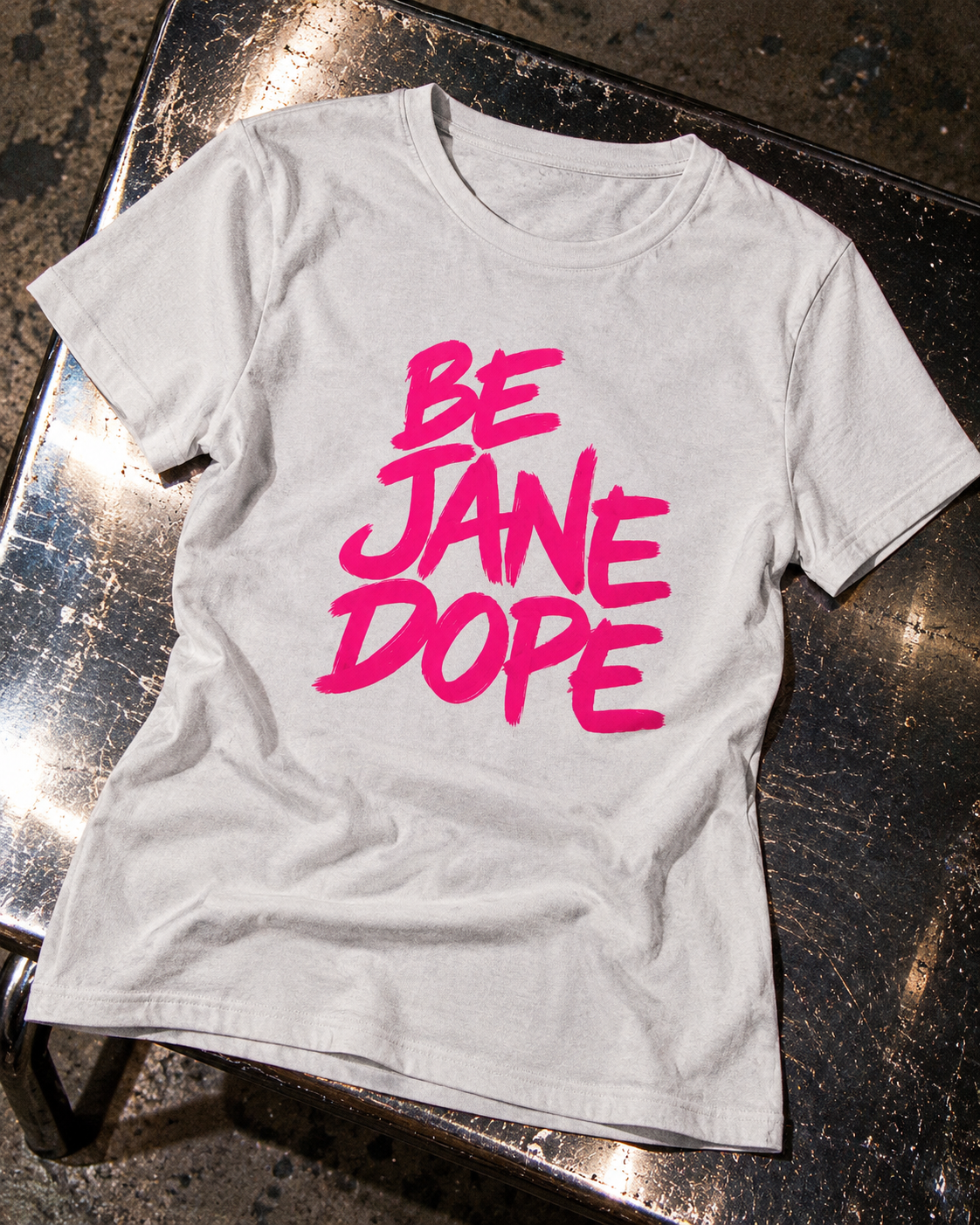Close-up of BE JANE DOPE front brush lettering and light-grey cotton fabric.
