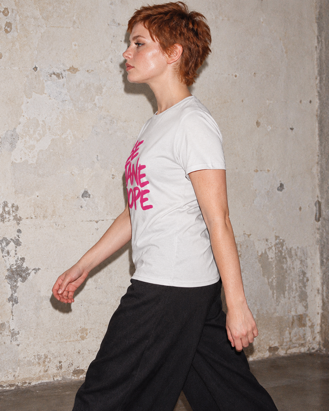Side profile of BE JANE DOPE short-sleeve cotton tee with black trousers.