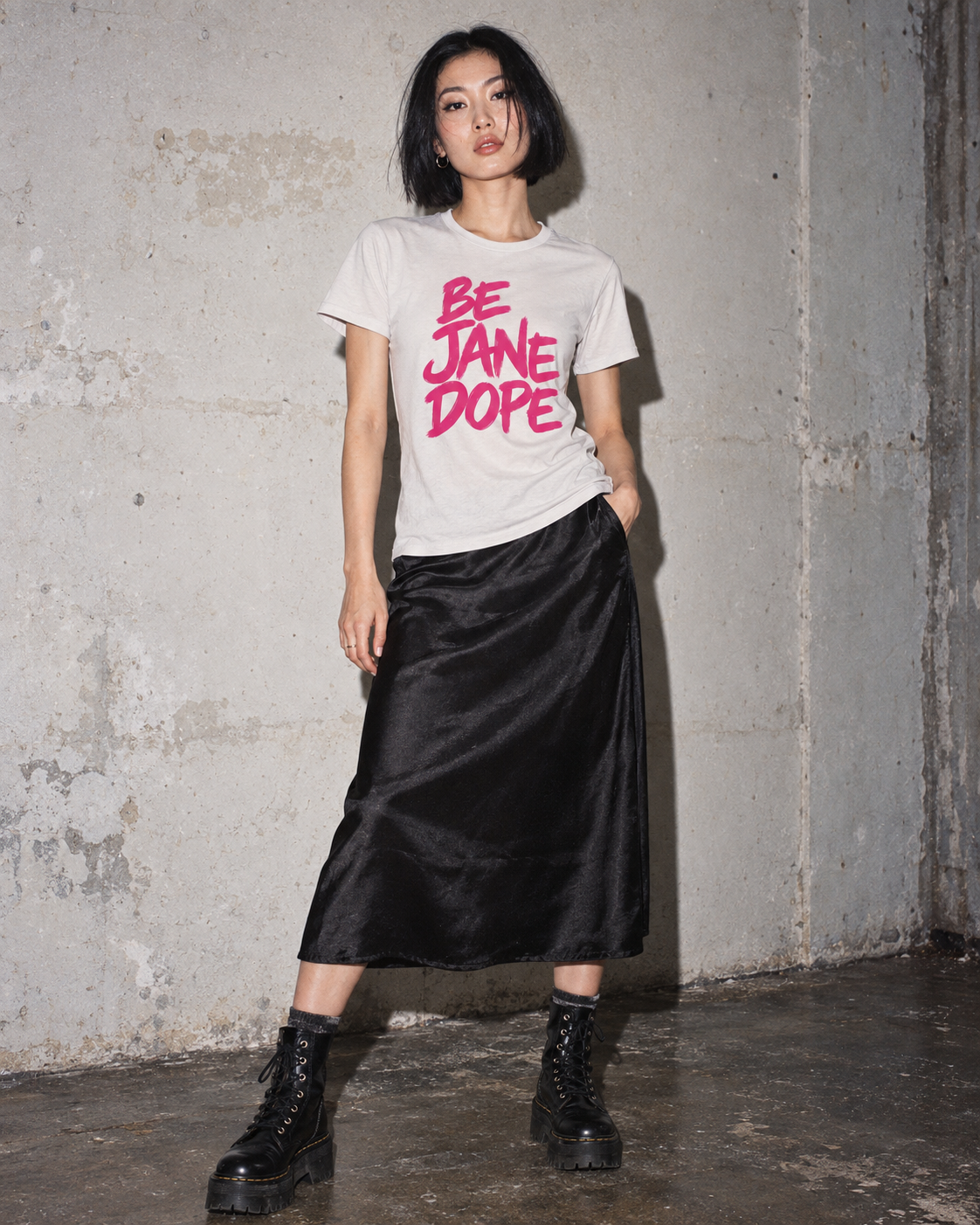 Front of BE JANE DOPE light-grey cotton tee with pink lettering, styled with a black satin skirt.