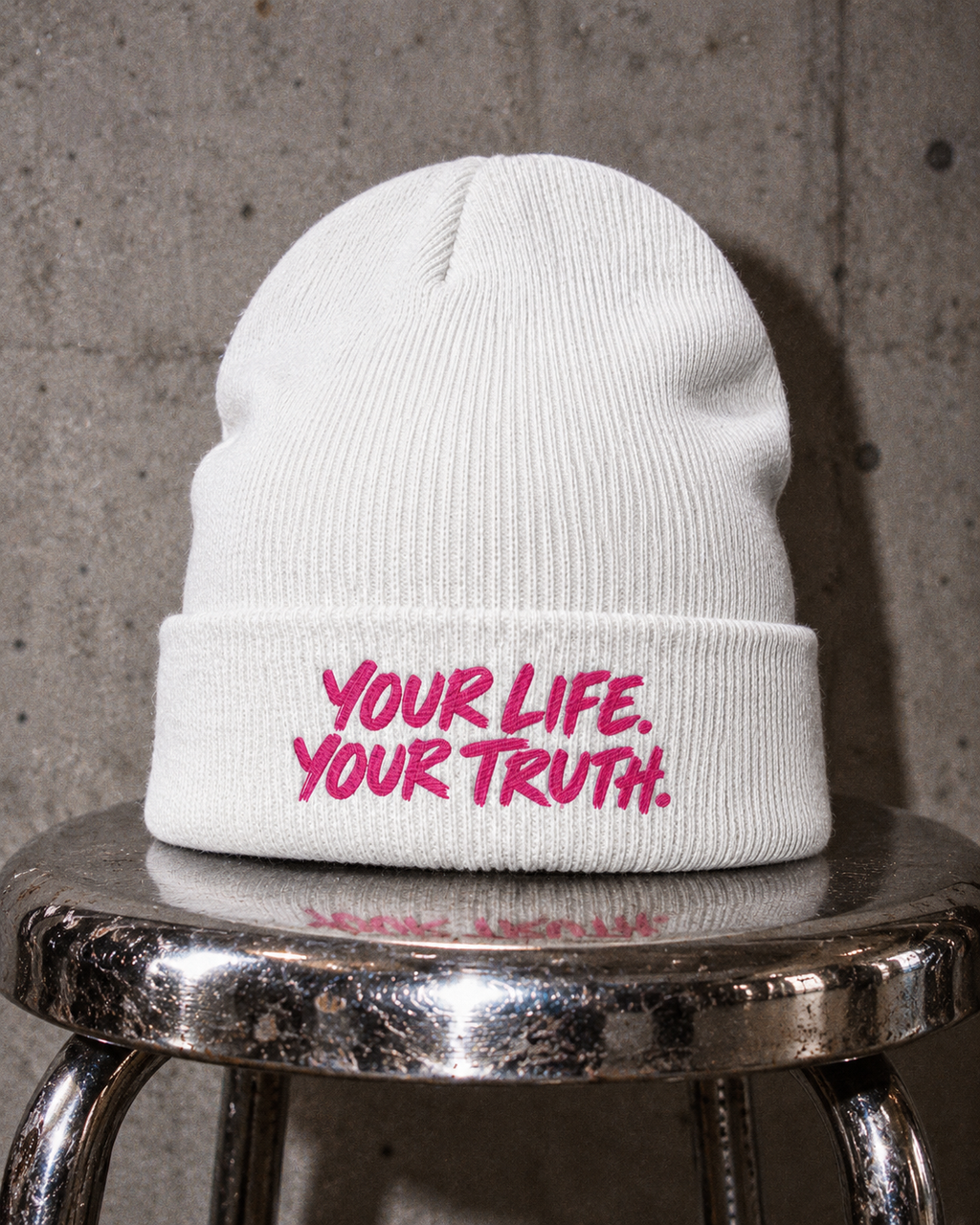 White BE JANE DOPE stitch beanie with pink YOUR LIFE. YOUR TRUTH. lettering on a chrome stool.