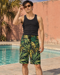 Big Buds men's green and yellow botanical board shorts styled with black ribbed tank and amber sunglasses.