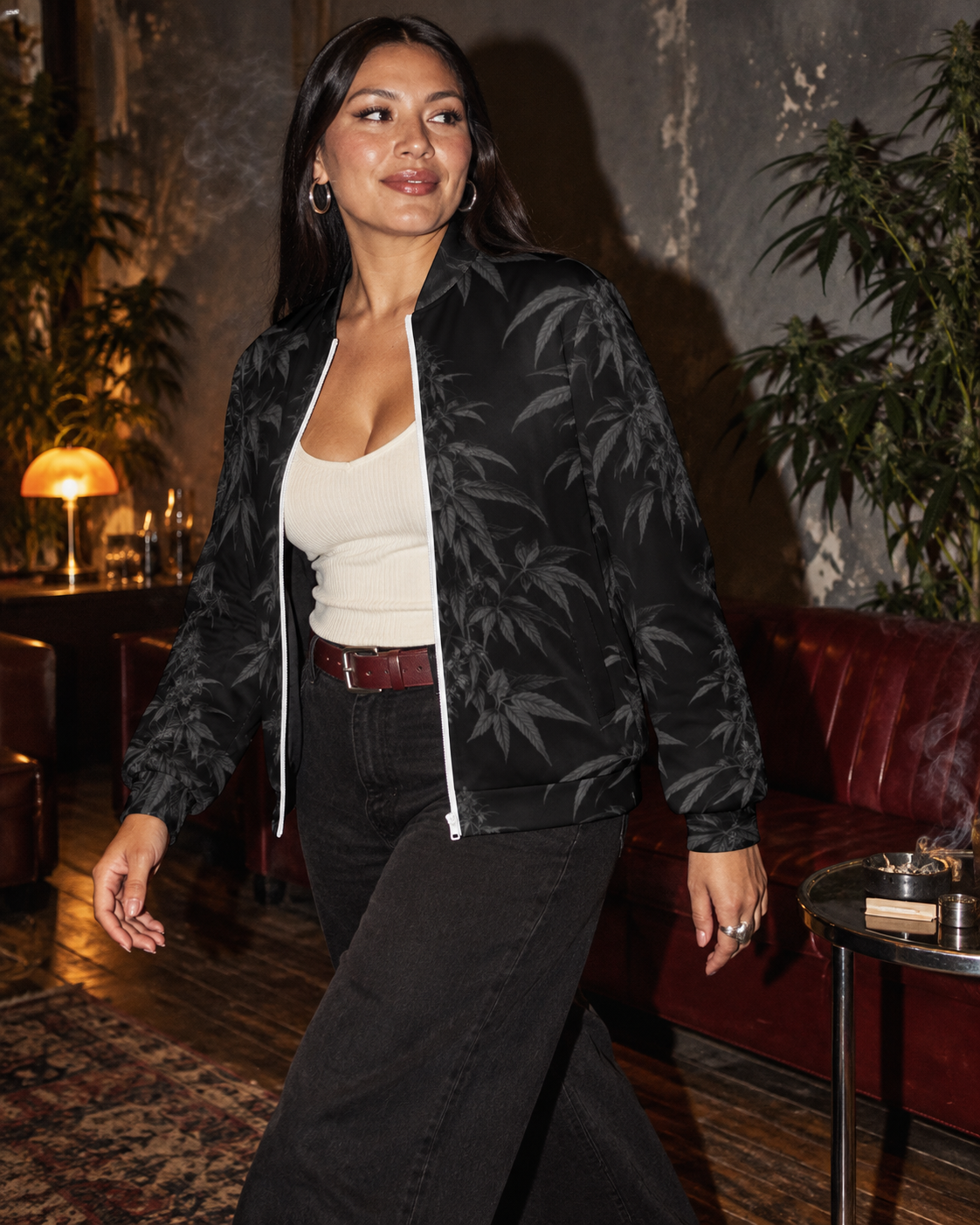 Black Widow jacket worn open over a cream tank, three-quarter walking view in a dark lounge.