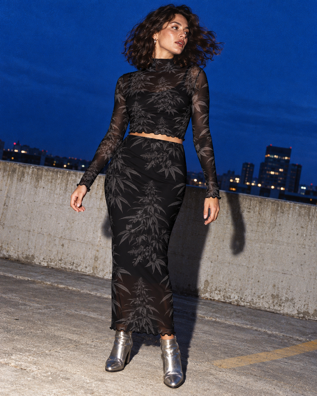 Black Widow mesh top and long skirt with silver boots in a flash-lit rooftop editorial.