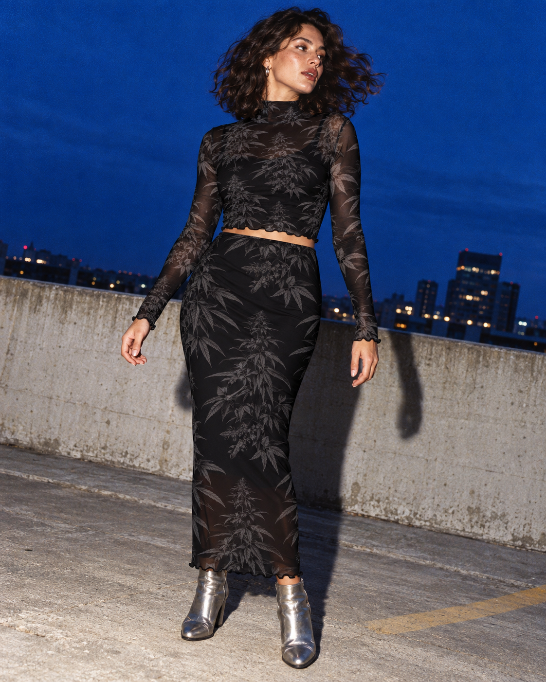 Black Widow mesh top and long skirt with silver boots in a flash-lit rooftop editorial.