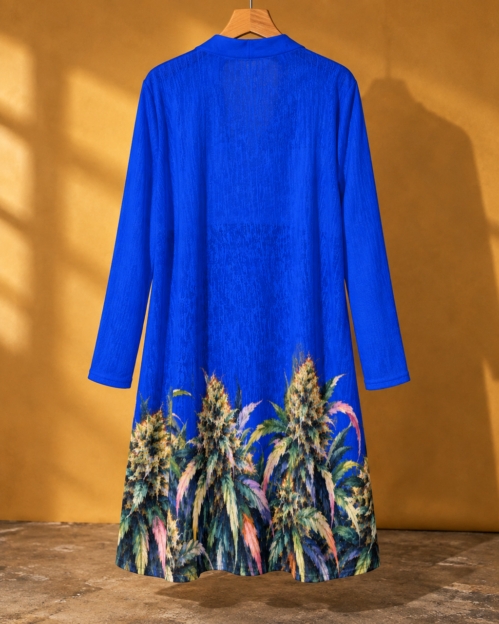 Full back of the Blue Mazar cardigan on a hanger, showing the blue sleeves and botanical hem border.