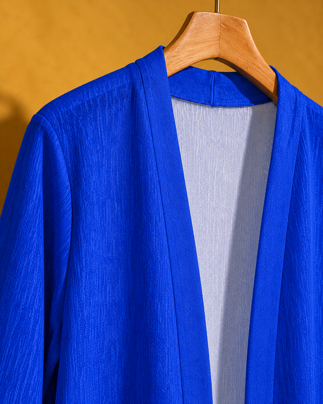 Blue Mazar cardigan neckline, shoulder seam and open-front band shown on a wooden hanger.