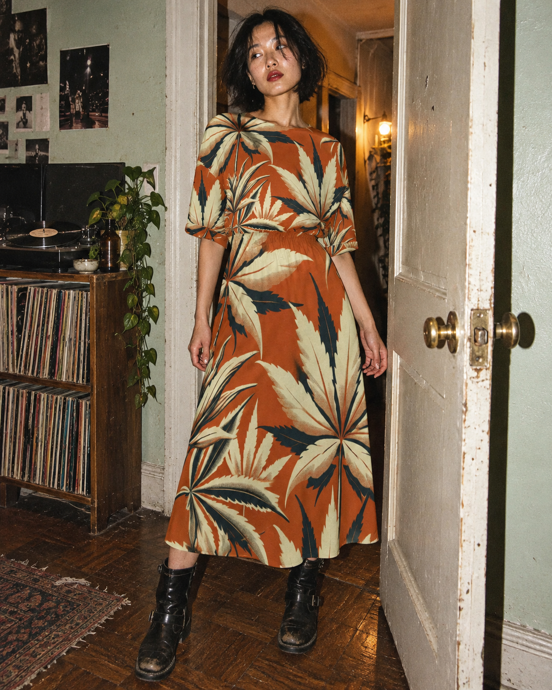 Jane Dope Cali Midi Pocket Dress in rust and cream leaf print, shown full length in an apartment doorway with black boots.
