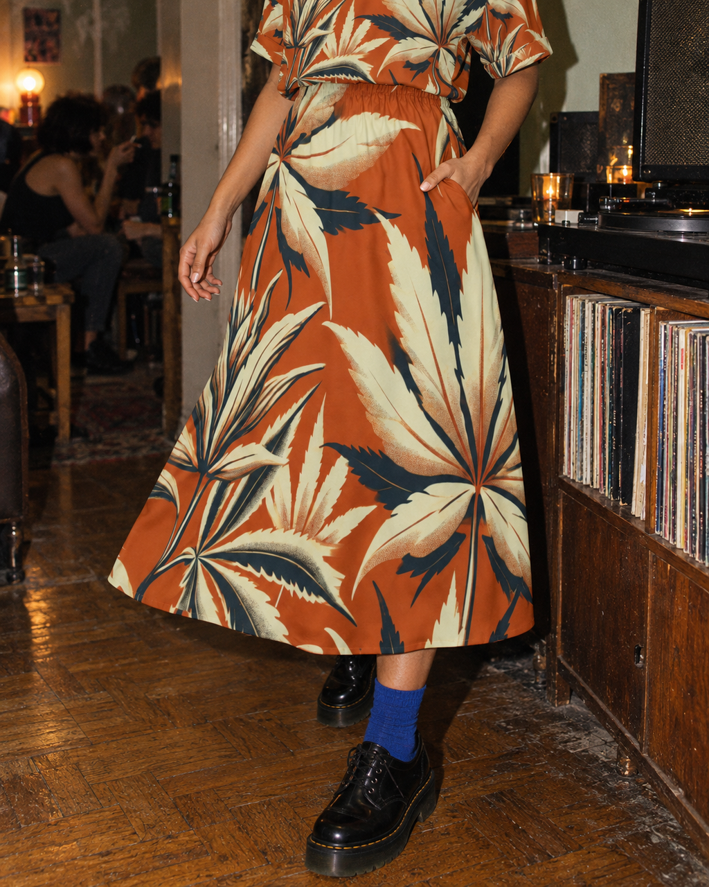 Cali Midi Pocket Dress skirt and continuous midi hem moving beside a record cabinet, styled with cobalt socks and black shoes.