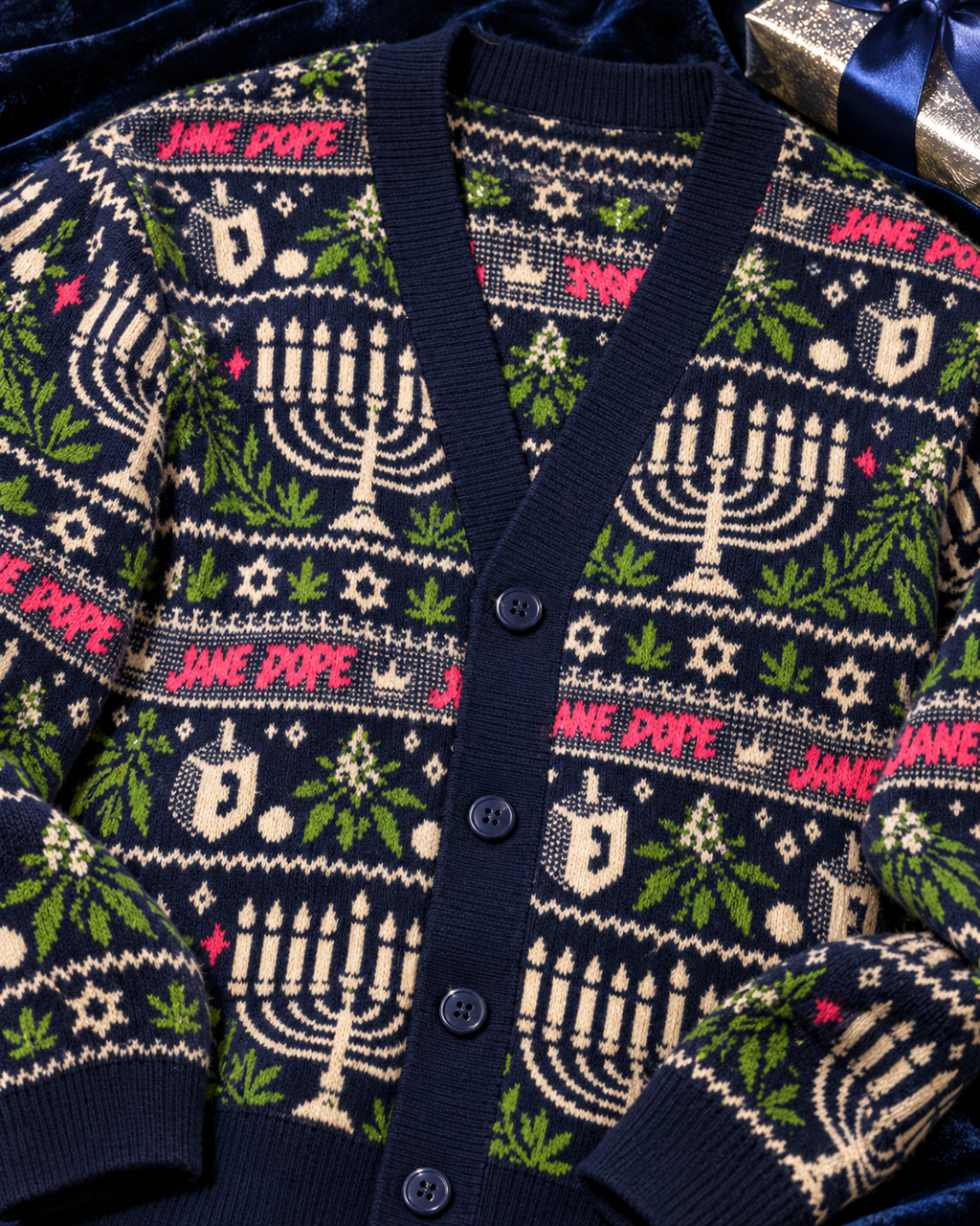 Close-up of Get Lit cardigan V-neck, buttons and knitted festive motifs on navy velvet.