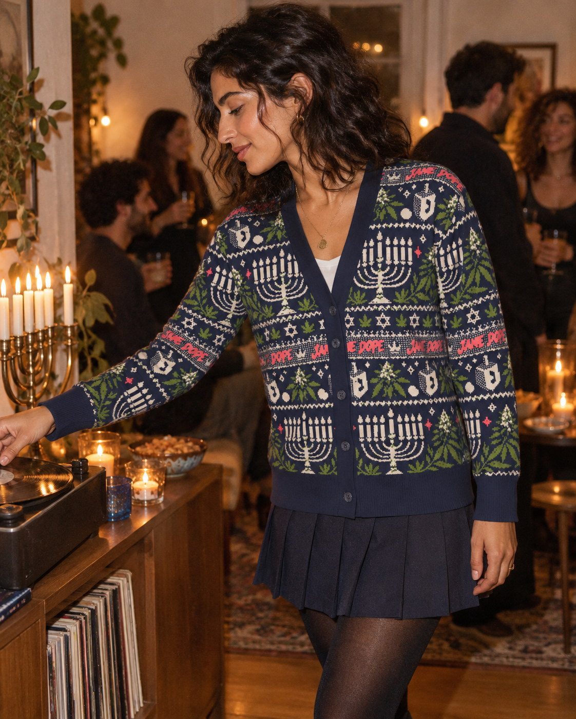 Three-quarter view of Get Lit cardigan styled with a navy skirt beside a record player.