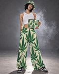 Model standing in Grass wide-leg pants and bucket hat, holding the matching Jane Dope stash pouch against a smoky gray studio backdrop.