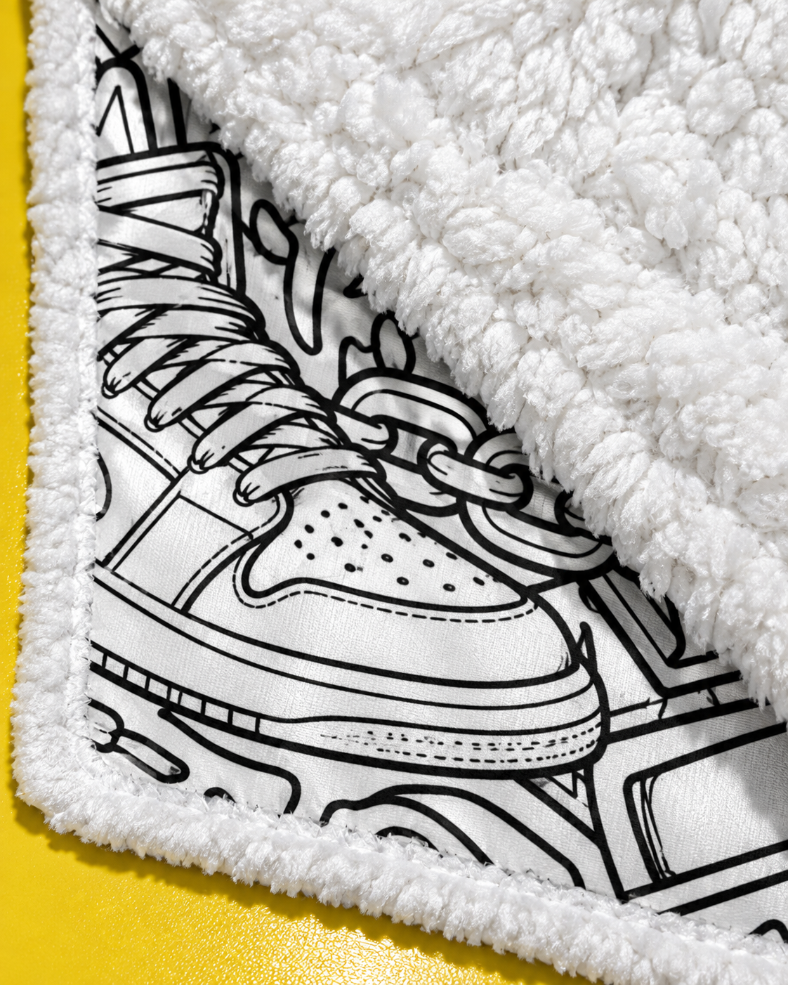 Close-up of the High Fashion blanket's printed sneaker motif, stitched edge and plush white fleece reverse