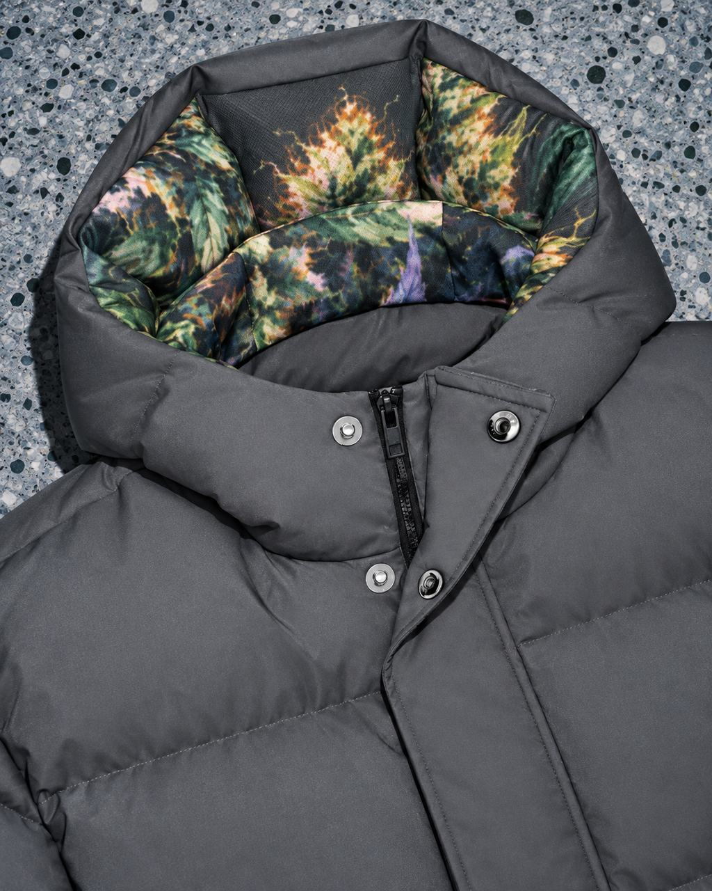 Long down jacket detail showing botanical hood lining, snap fasteners and concealed zip