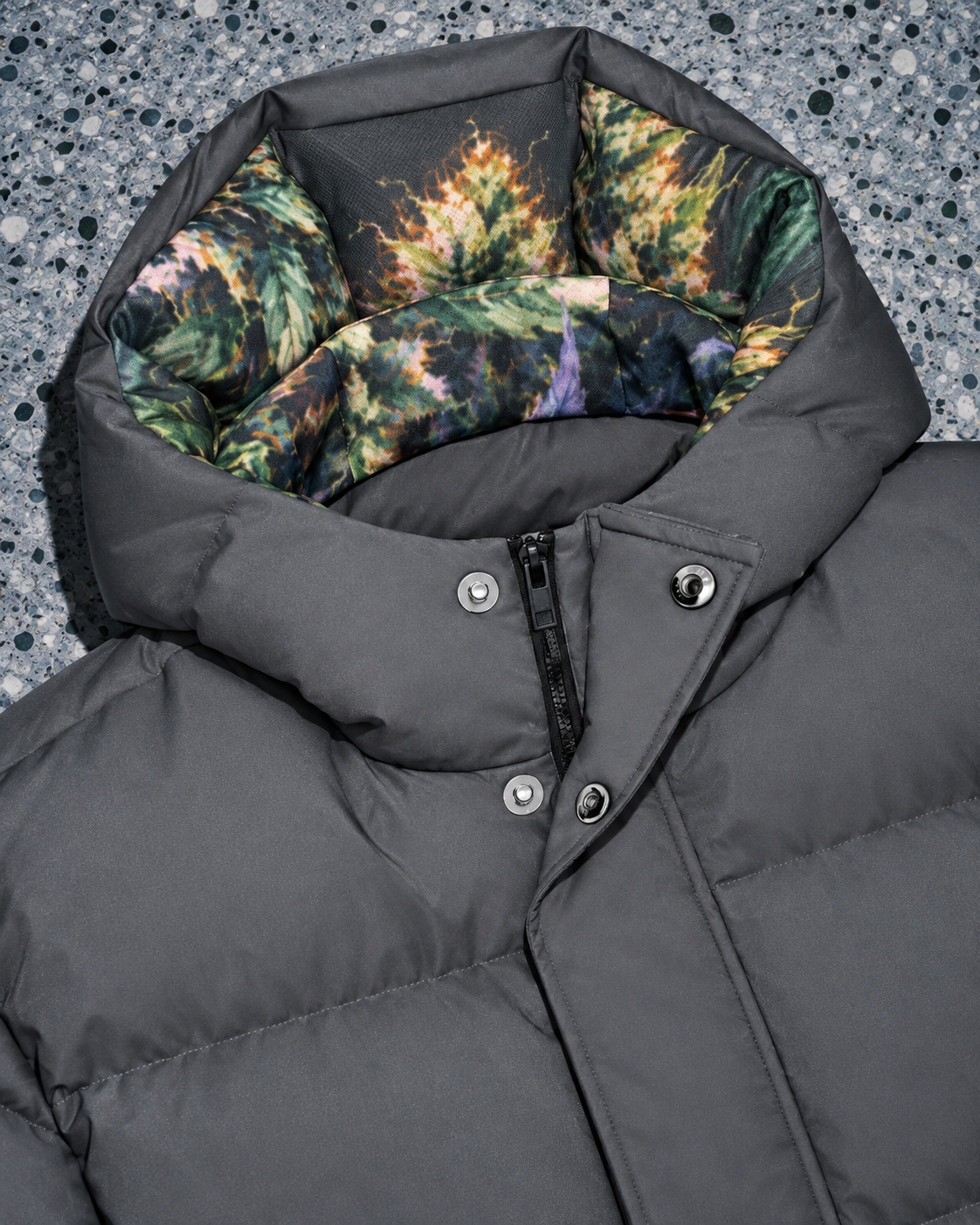Long down jacket detail showing botanical hood lining, snap fasteners and concealed zip