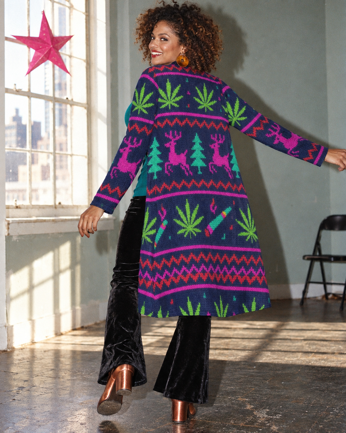 Back view of the Neon Xmas Mid-Length Cardigan in a flash-lit holiday editorial, showing pink reindeer, teal trees and Herb motifs.