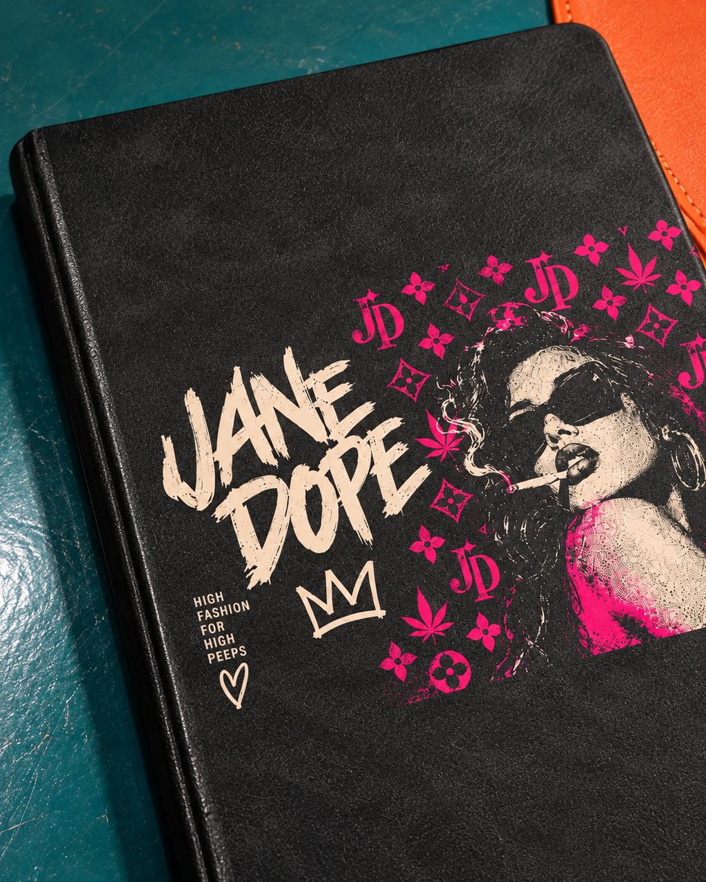 Close-up of the cream and pink Jane Dope artwork on the black PU notebook cover. AI editorial illustration; props not included.