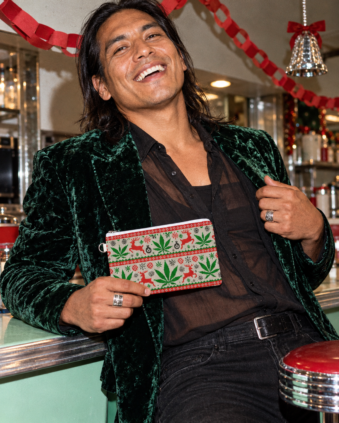 OG Xmas Stash Pouch held by a model in a green velvet jacket at a festive diner counter