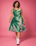 Pink Haze botanical skater dress, walking front view with a curly bob and white high-top sneakers.