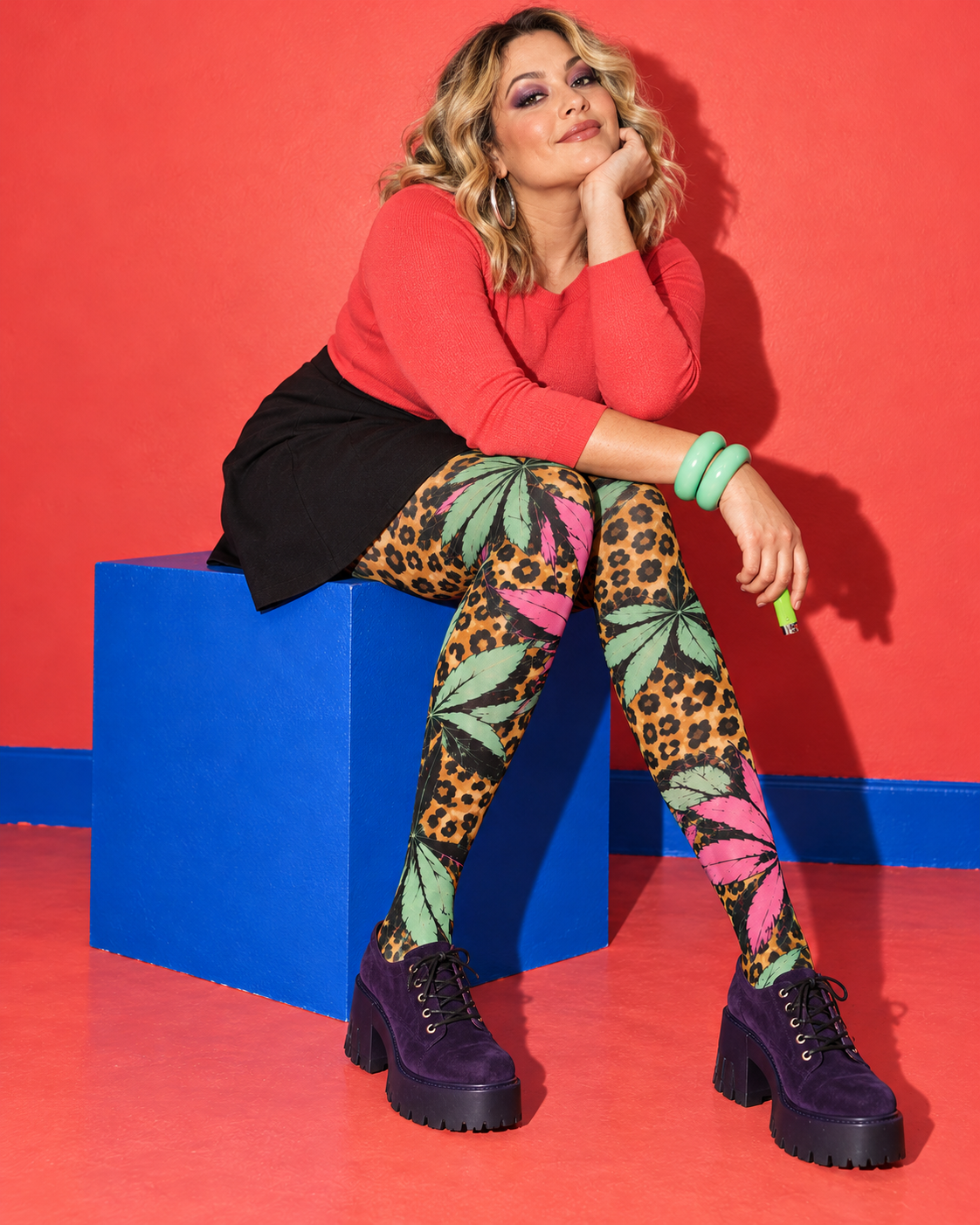 Runtz pink and mint botanical leopard tights, seated on a cobalt block with purple platform shoes. AI editorial illustration; styling accessories not included.