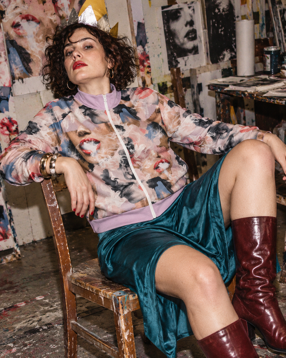 Squad jacket editorial mockup, model lounging in a paper crown with teal satin skirt and burgundy boots.