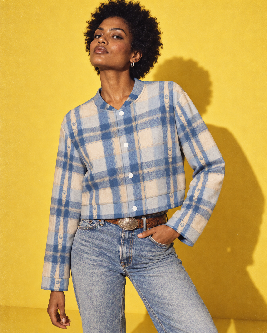 Sunday Sesh blue-and-cream plaid cropped jacket, closed front with four white snaps, denim and a Western belt on yellow.
