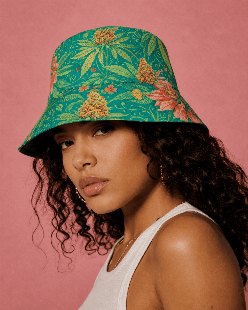 Woman wearing a green floral bucket hat against a pink background