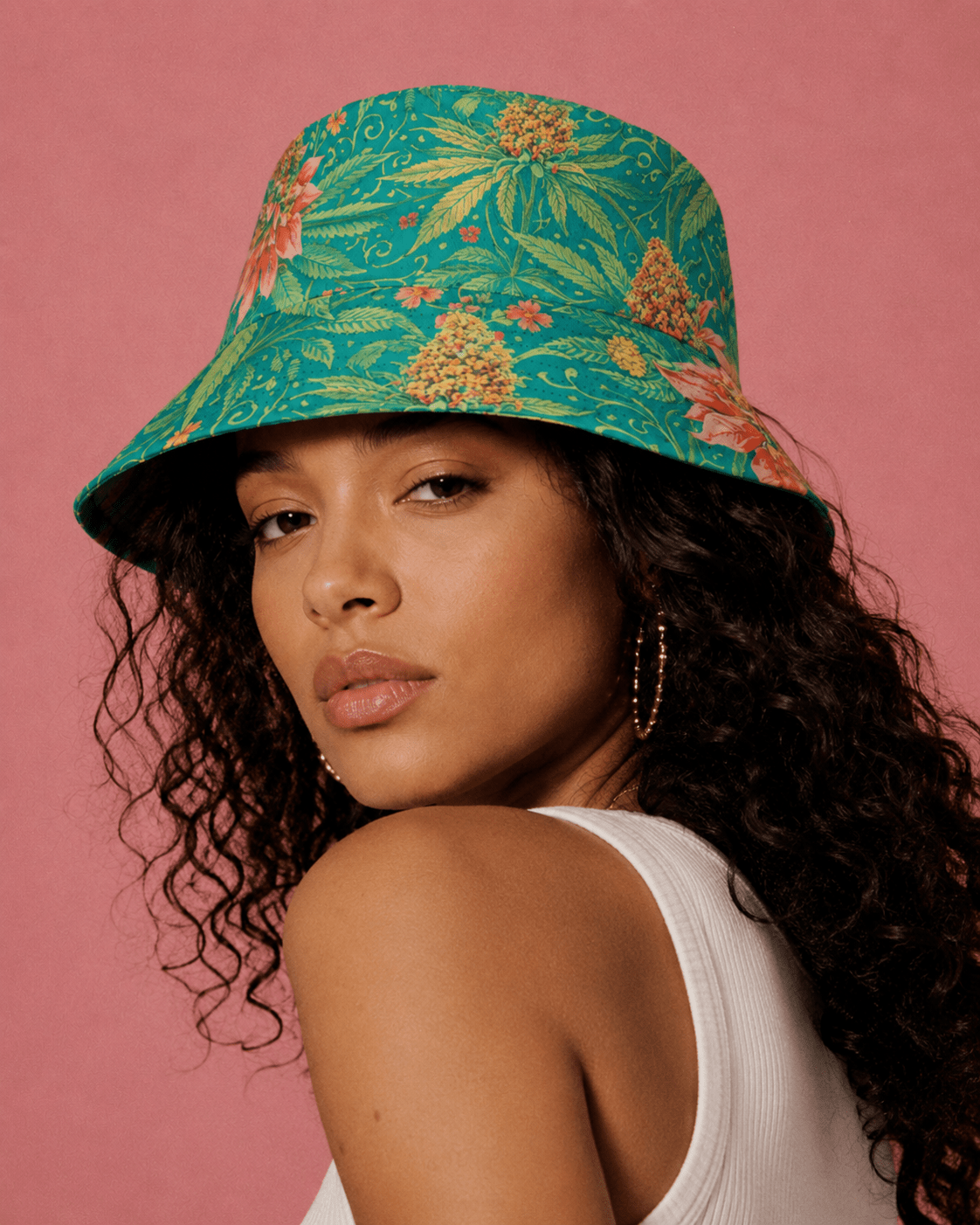 Woman wearing a colorful floral bucket hat against a pink background