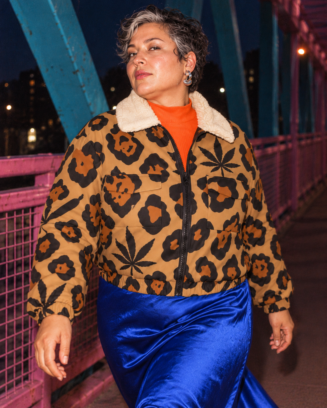 Front view of the Leopard jacket on a pink and turquoise bridge at night, with a cobalt skirt.