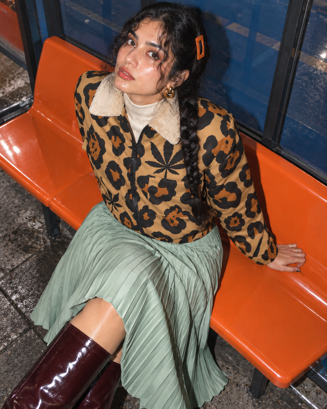 Leopard jacket with black and rust rosettes, Herb leaves and a cream collar. Overhead orange bench with seafoam skirt; shoulder-to-hem editorial.