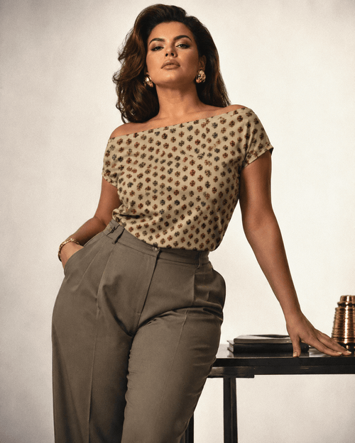 Woman wearing a patterned top and high-waisted pants against a neutral background